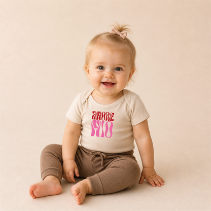 Amore Mio Bügelbild auf beigem Baby-Body – sitzendes Baby