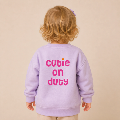 Cutie on Duty Bügelbild auf lilanem Kleinkind-Sweater – Rücken